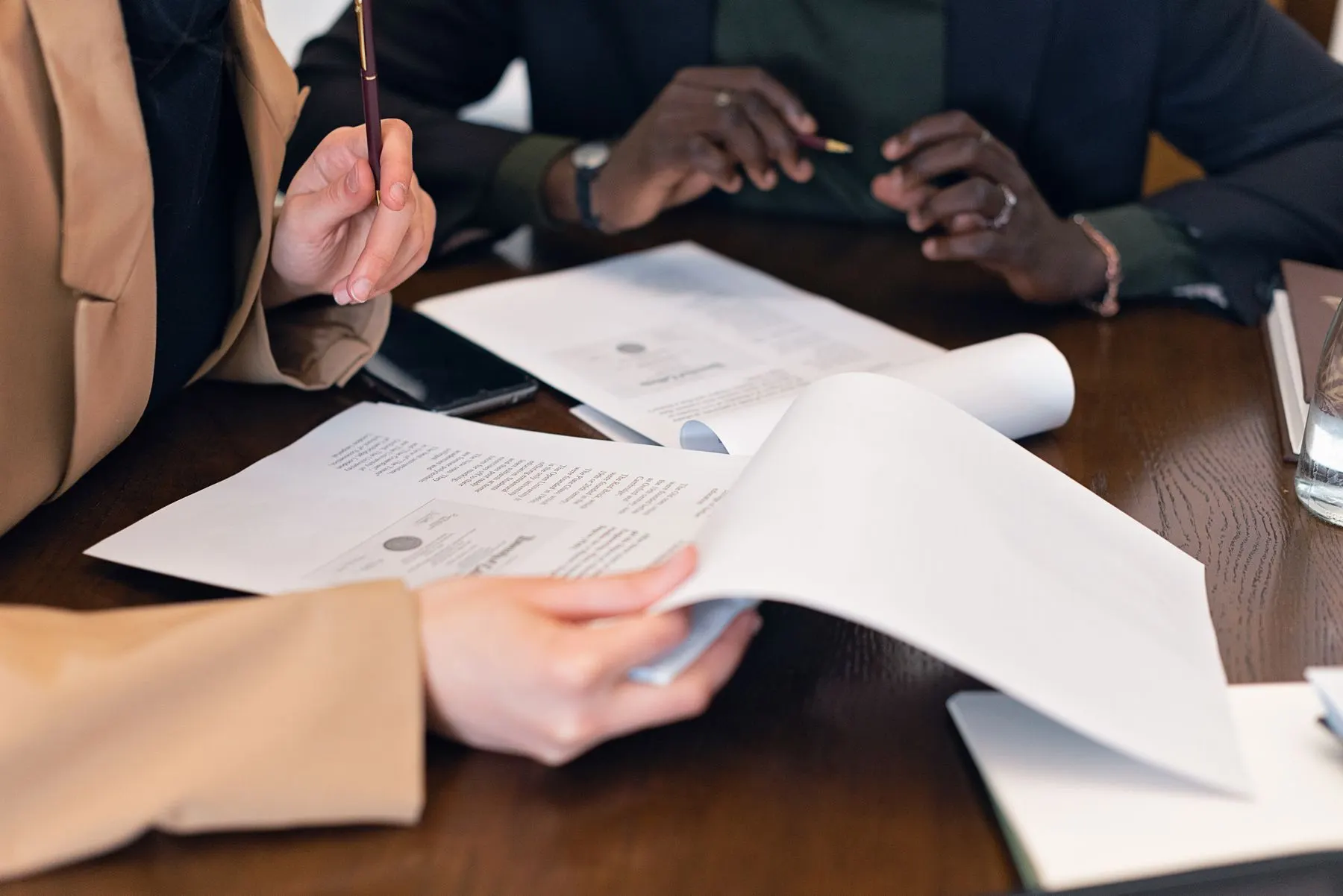 Two people reviewing printed documents across a meeting table